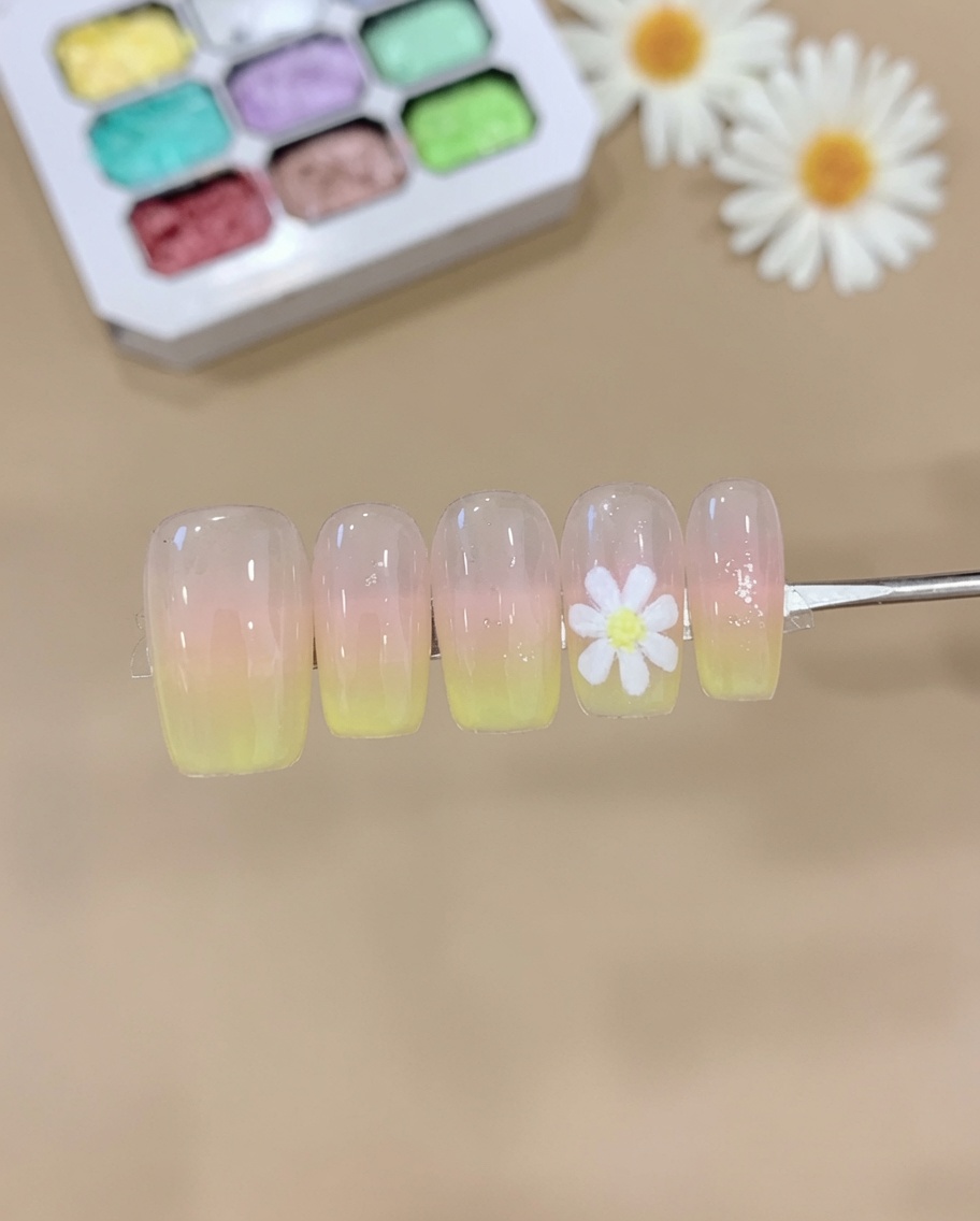 Une éponge appliquant du gel rose et jaune sur une capsule dongle, créant un dégradé ombré doux.