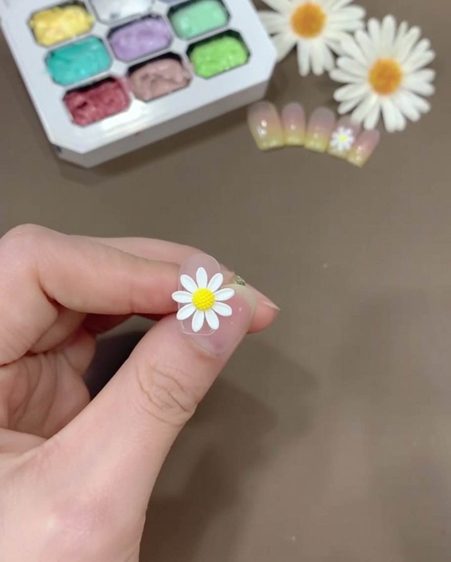 Une petite quantité de gel jaune mélangée avec du base coat transparent sur une palette en plastique.