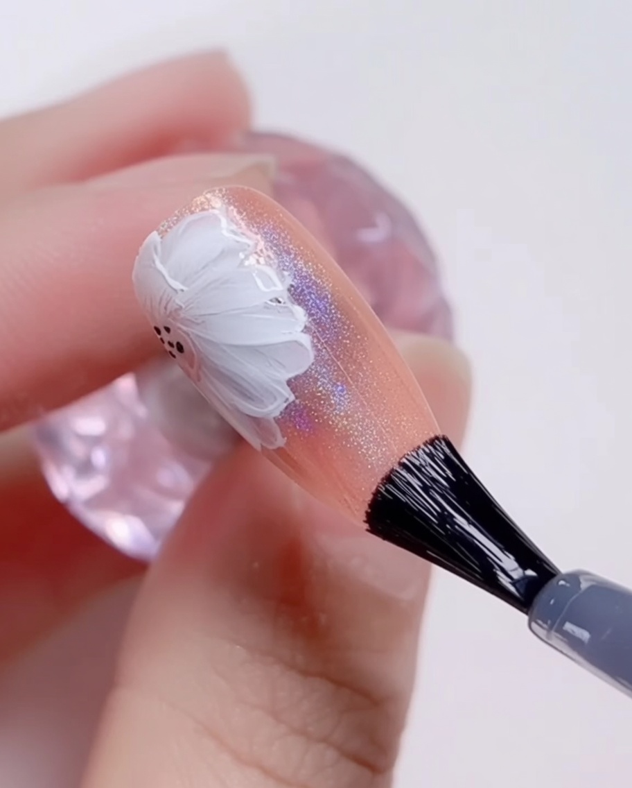 Un pinceau appliquant un top coat brillant sur le design final de marguerite.