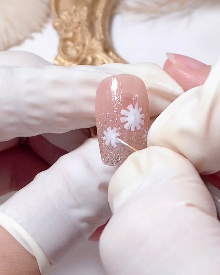 Gros plan dun outil de dotting touchant le centre dune marguerite blanche sur un ongle.