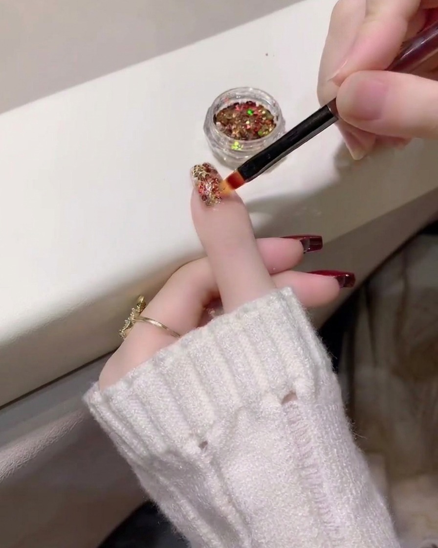 Gros plan montrant une couche dense de paillettes multicolores appliquée sur longle de lannulaire.
