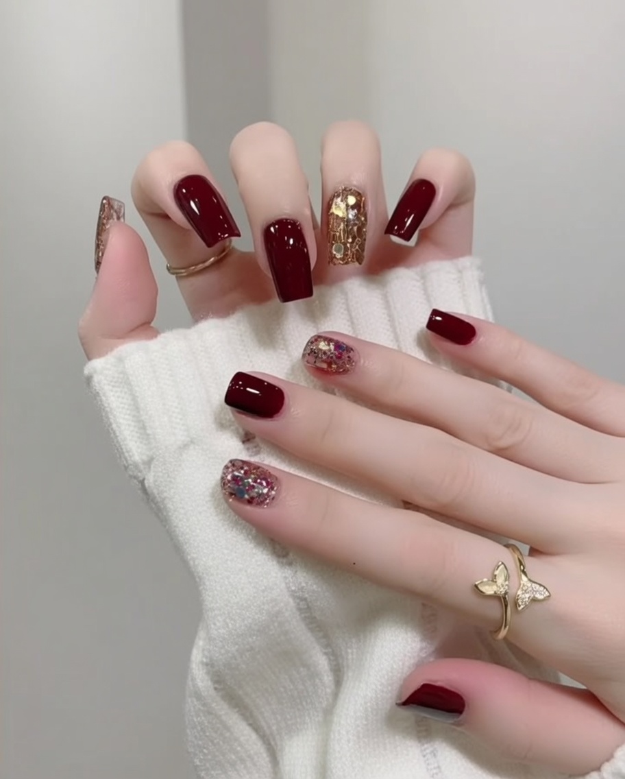 Une main aux ongles rouges brillants et pailletés reposant à lintérieur dune lampe UV/LED pour la catalysation finale.