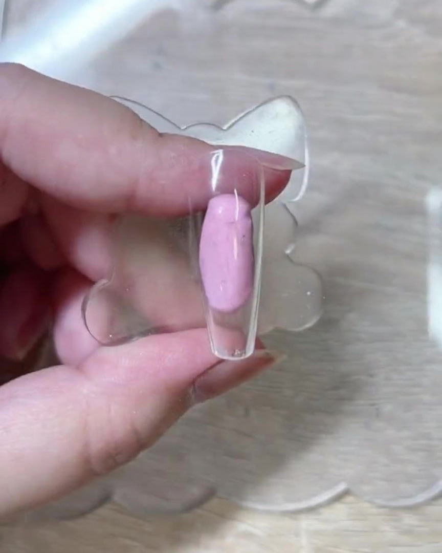 Gros plan sur un pinceau liner traçant délicatement les contours blancs de roses sur une capsule dongle nue et transparente.
