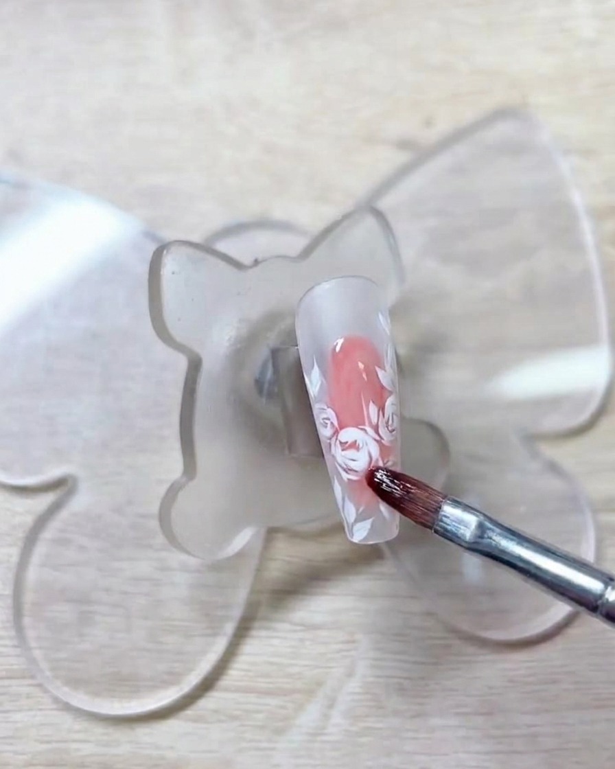 Un pinceau appliquant un gel rouge clair sur les contours blancs précédemment tracés.