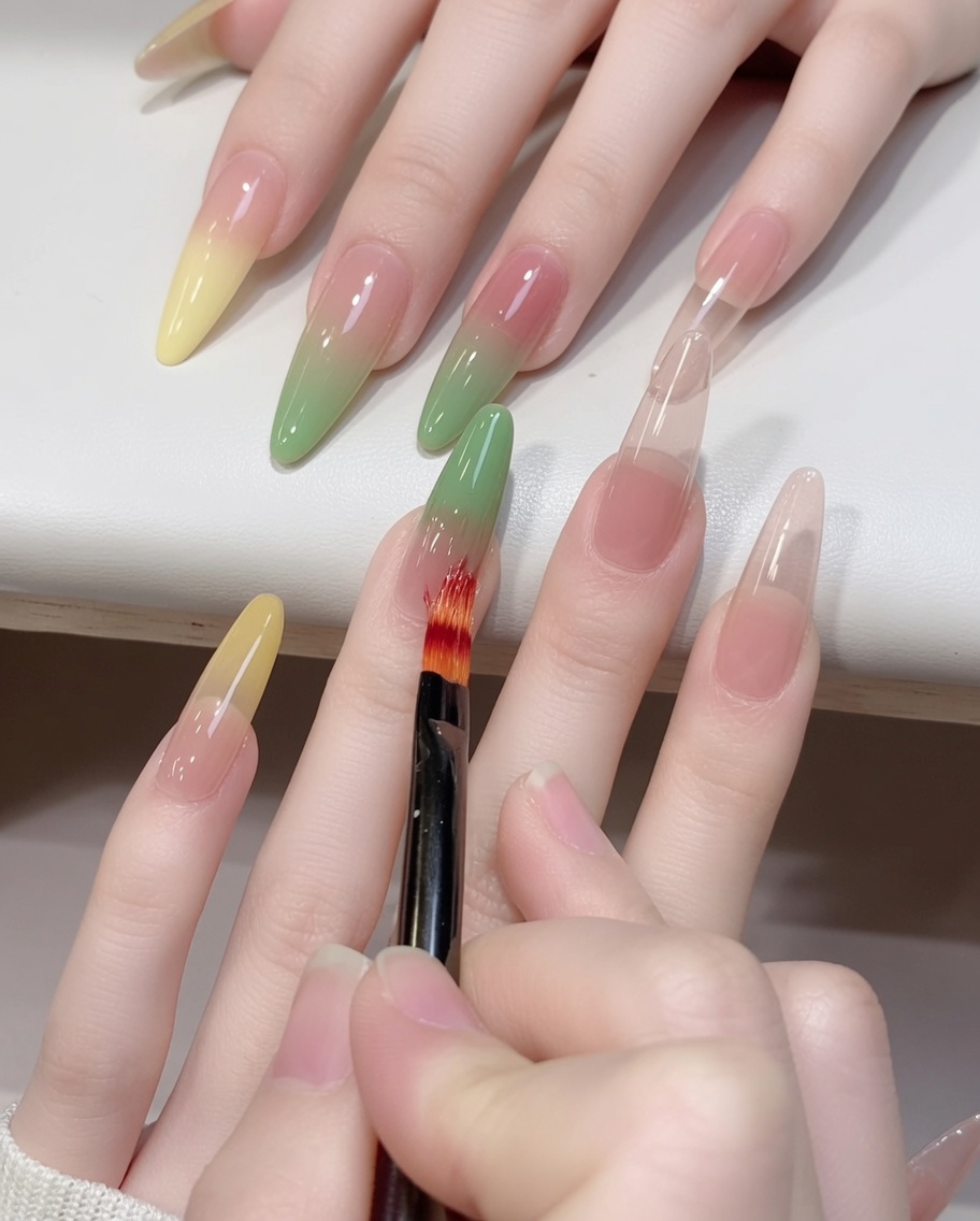 Gros plan dun pinceau ombré estompant du gel vert vers le haut sur un ongle.
