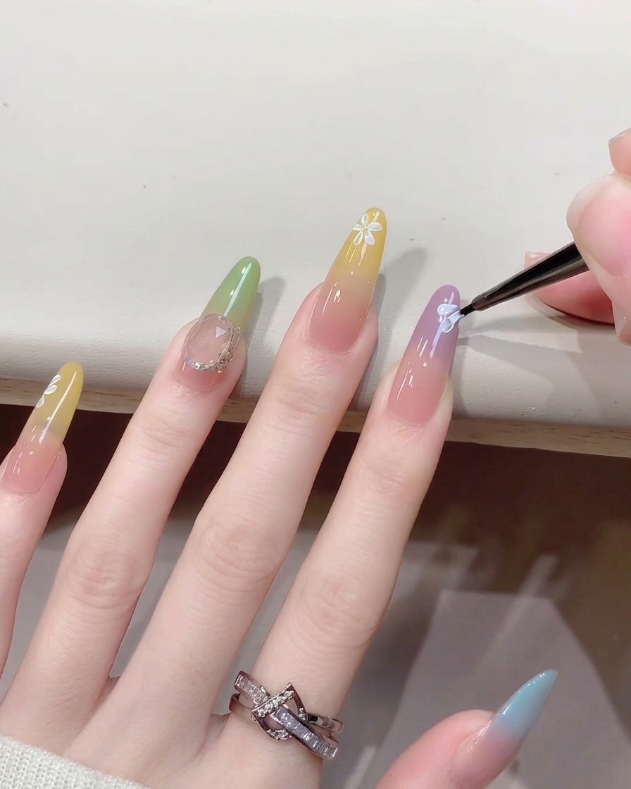 Vue rapprochée dun pinceau fin ajoutant de petits points blancs au centre dun nail art représentant une fleur peinte.
