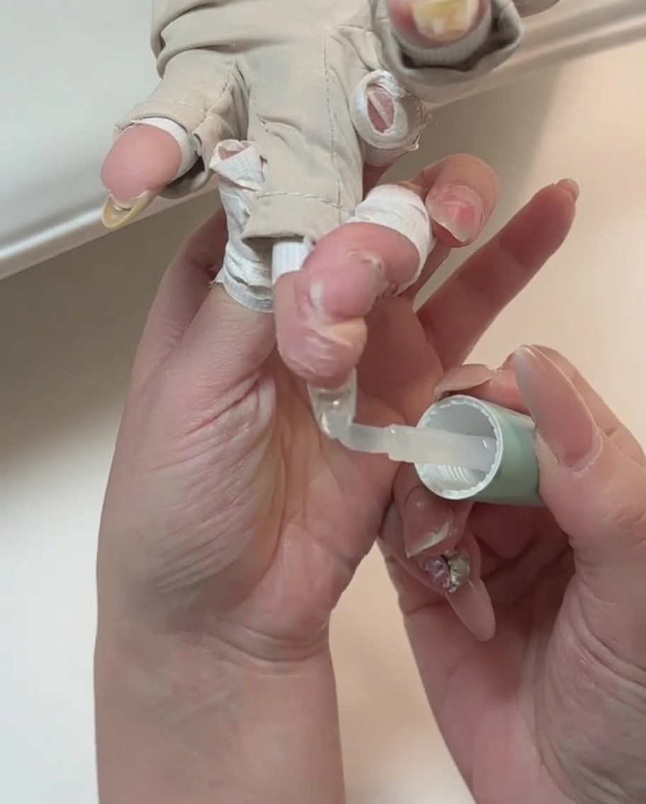 Gros plan dun pinceau appliquant un top coat transparent sur un ongle.