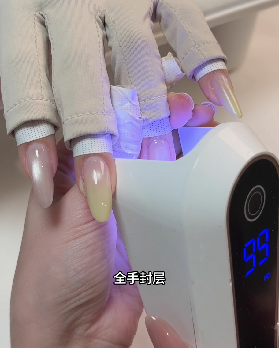 Une main positionnée dans une lampe UV professionnelle durant la catalysation.
