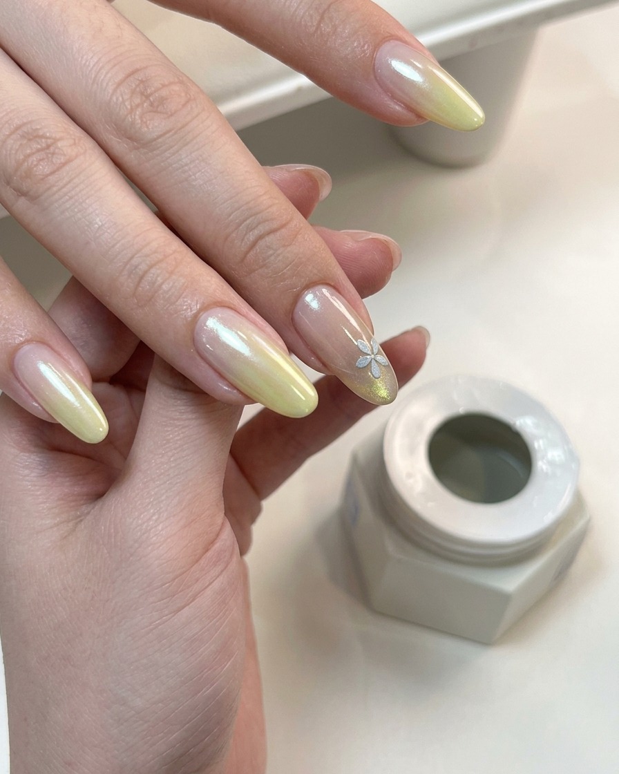 Une main avec un nail art floral et dégradé catalysant sous une lampe UV.