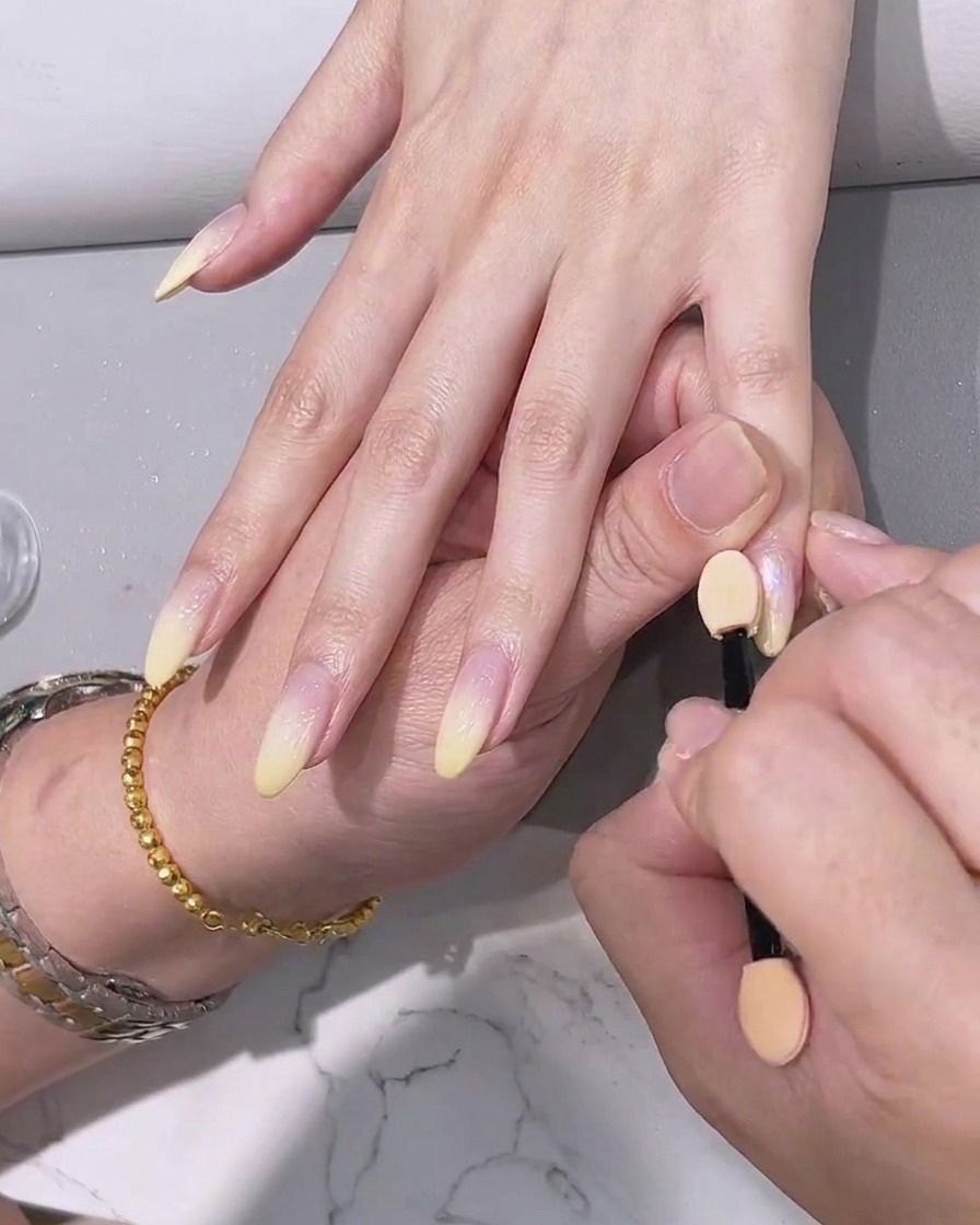 Application dun top coat transparent final sur les ongles à effet chrome.
