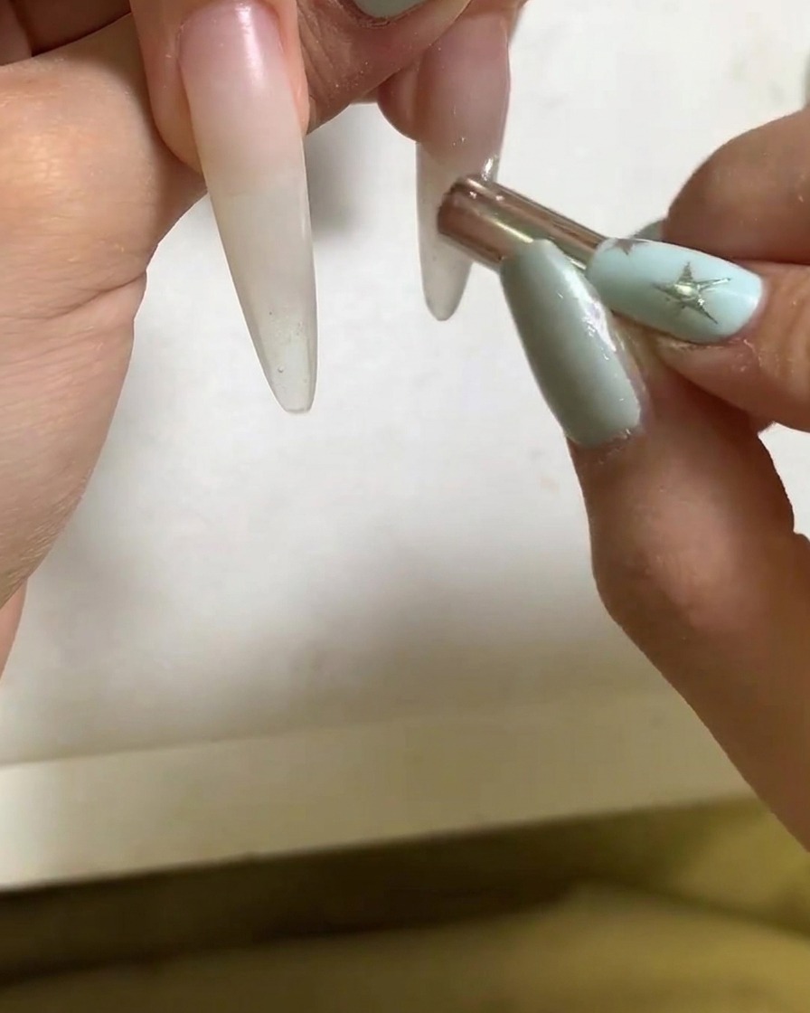 Un petit bâtonnet magnétique façonnant le reflet lumineux sur un ongle verni.