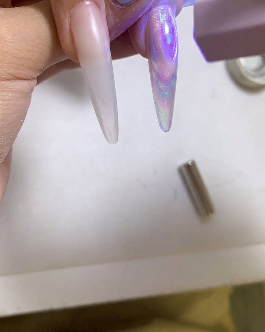 Une lampe UV/LED portable catalysant un ongle en gel cat eye brillant.