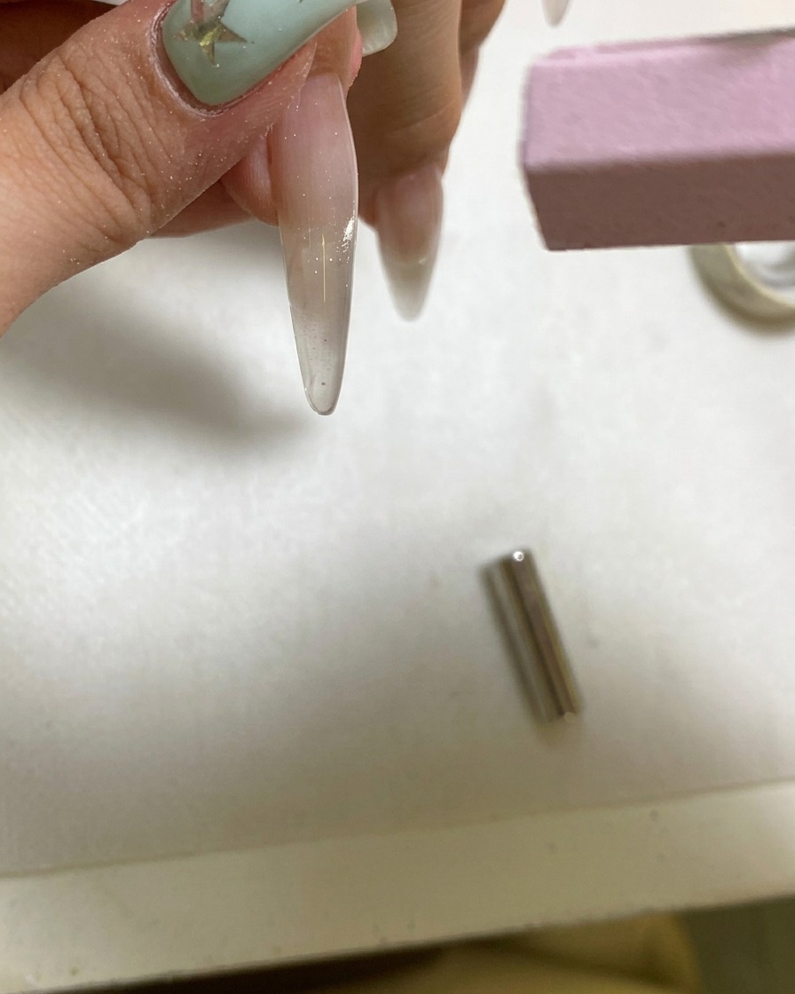 Une petite lampe UV portative catalysant un ongle en gel fraîchement magnétisé.