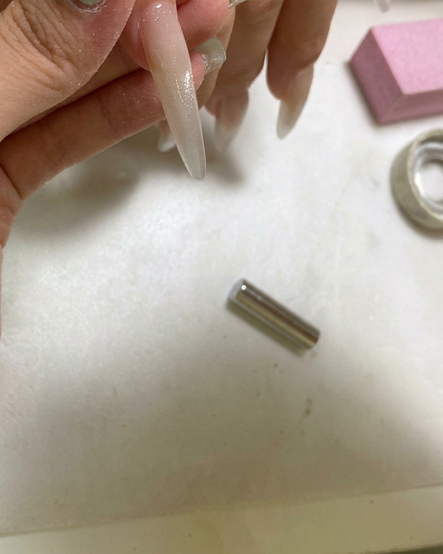 Une lampe UV portative catalysant un ongle stylisé avec un effet cat eye boule de verre.