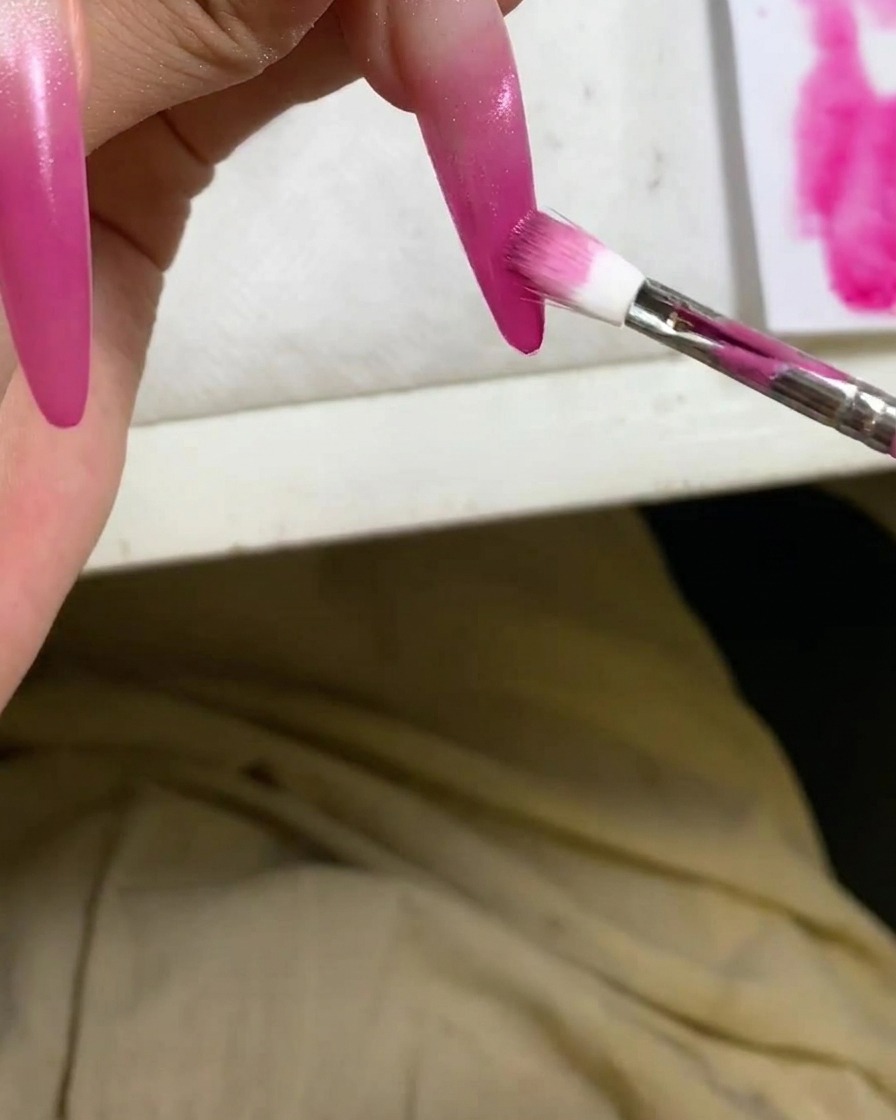 Vue détaillée dun applicateur éponge approfondissant le dégradé ombré rouge sur le bout dun ongle.