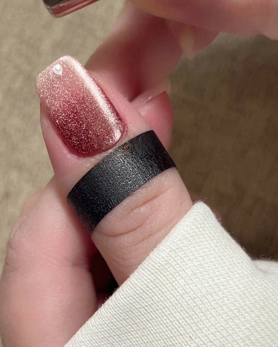 Un aimant positionné près de longle, incitant les particules magnétiques du vernis beige à converger en une large bande lumineuse.