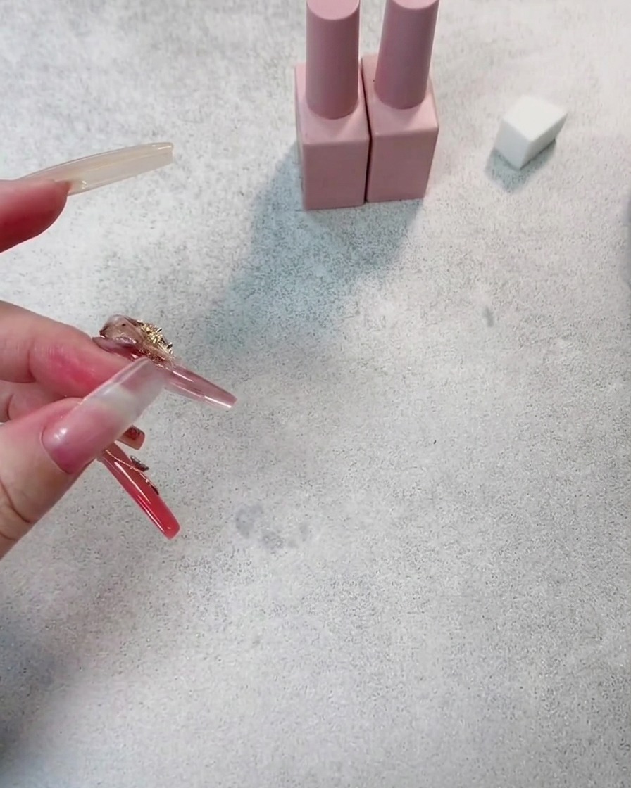 Gros plan sur un ongle recevant une seconde couche de vernis gel rouge foncé, montrant une profondeur de couleur accrue.
