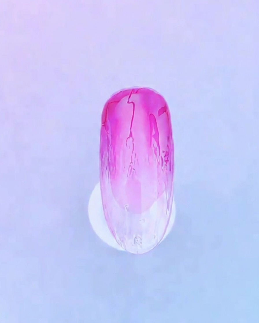 Gros plan dun pinceau appliquant une couche claire et homogène de gel de base par-dessus le design dégradé rose.