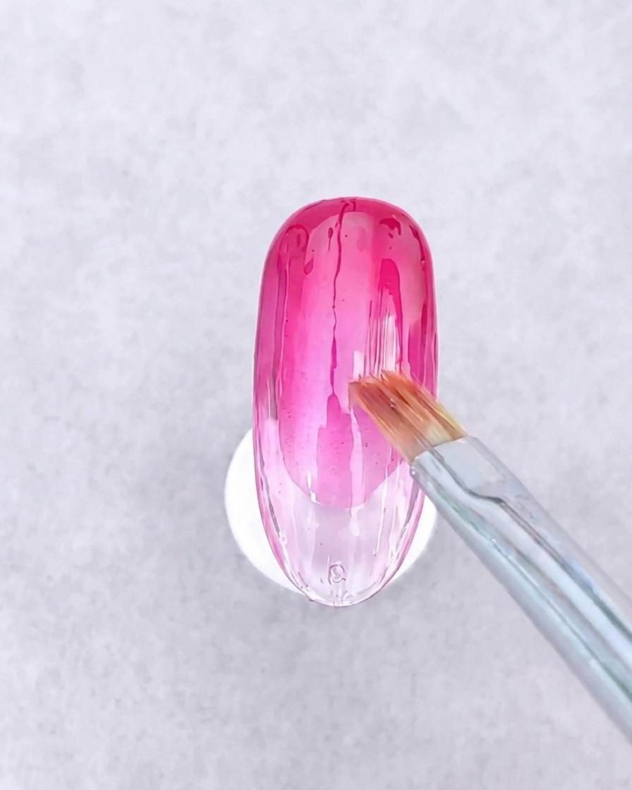 Une paire de brucelles positionnant de petits morceaux géométriques de papier verre et de fines lignes métalliques dorées sur une surface en gel humide.