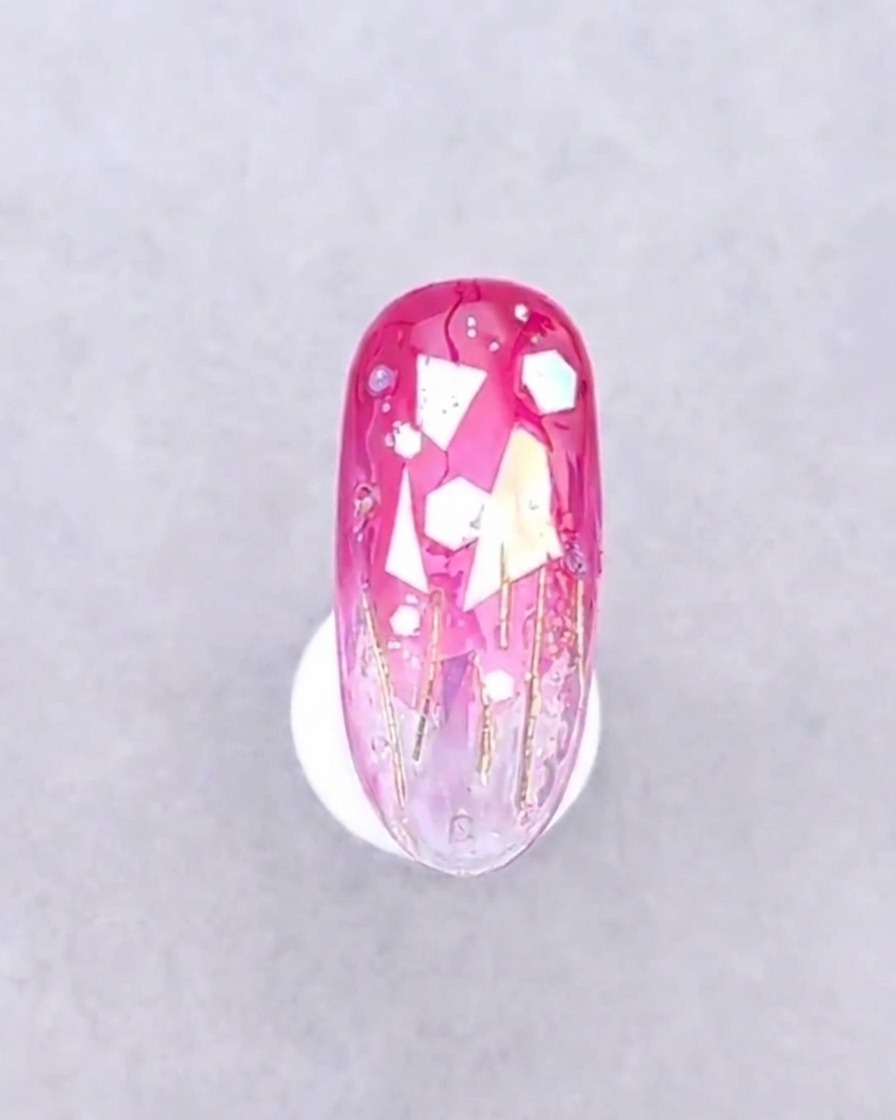 Un ongle orné de ses décorations placé sous la lueur violette dune lampe à ongles UV.
