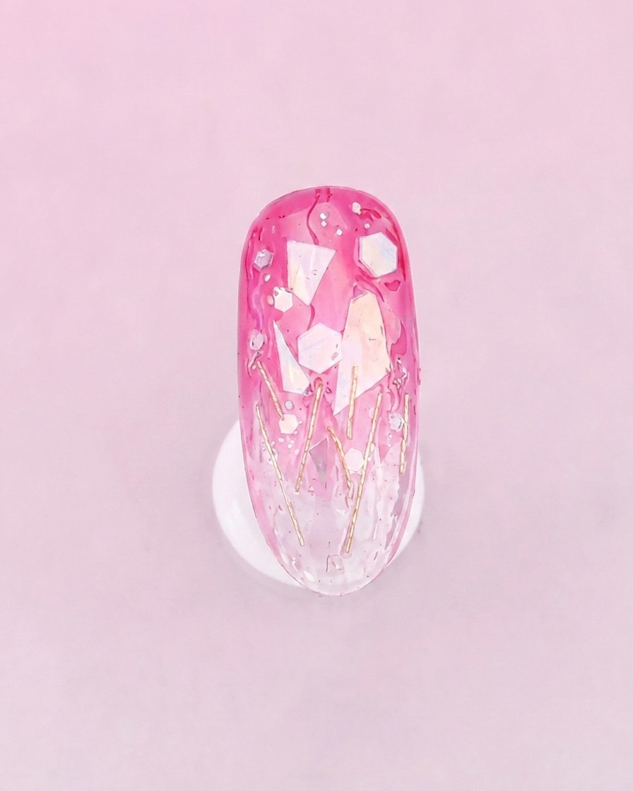 Un pinceau appliquant une couche plus épaisse de gel transparent par-dessus longle décoré pour unifier la texture.