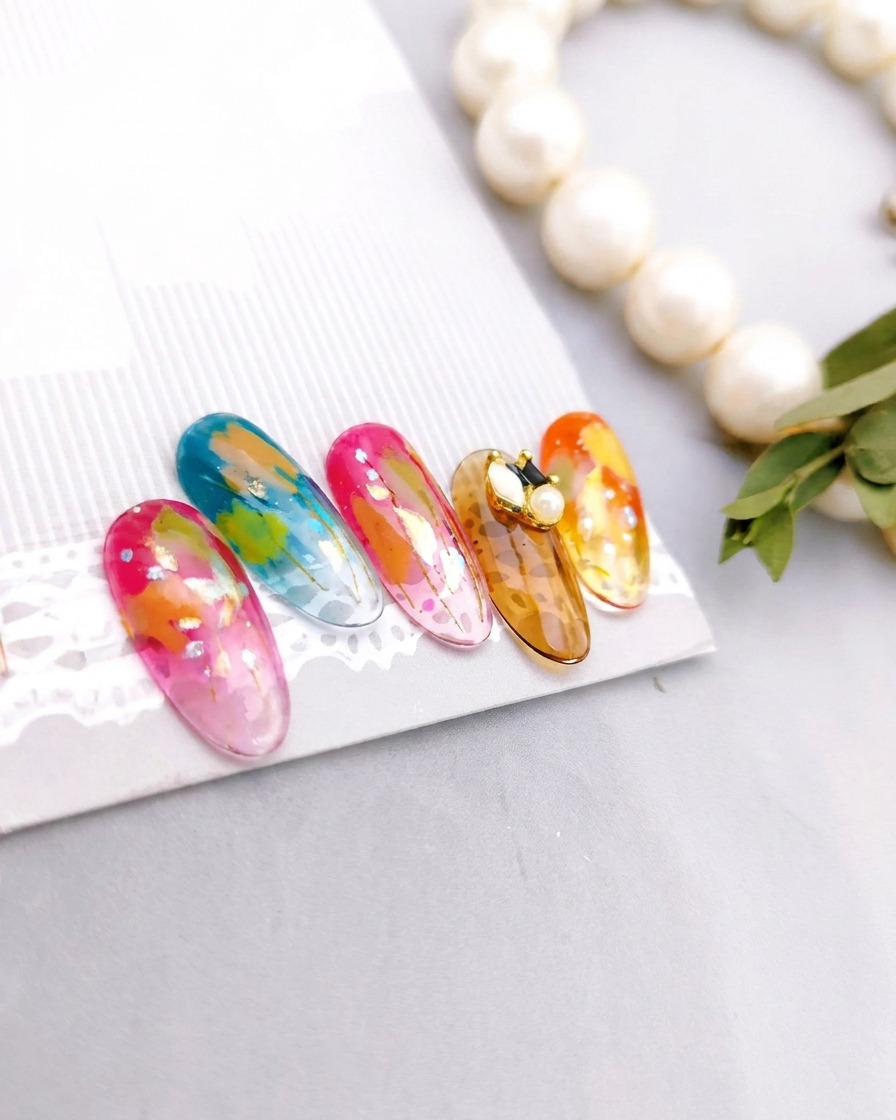 Un ensemble de cinq ongles terminés, arborant chacun des motifs artistiques uniques, disposés sur un présentoir après une catalyse complète.