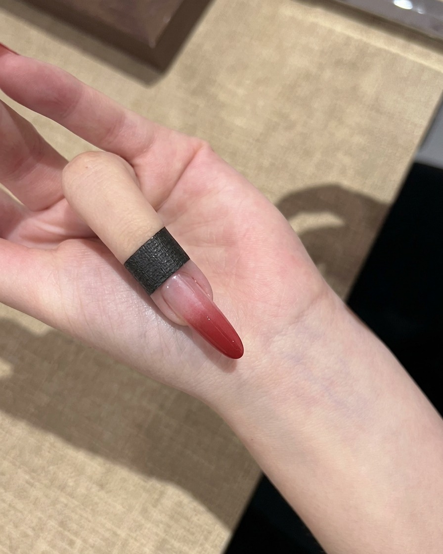 Un seul ongle montrant un effet de dégradé rouge catalysé passant du rouge foncé au transparent.