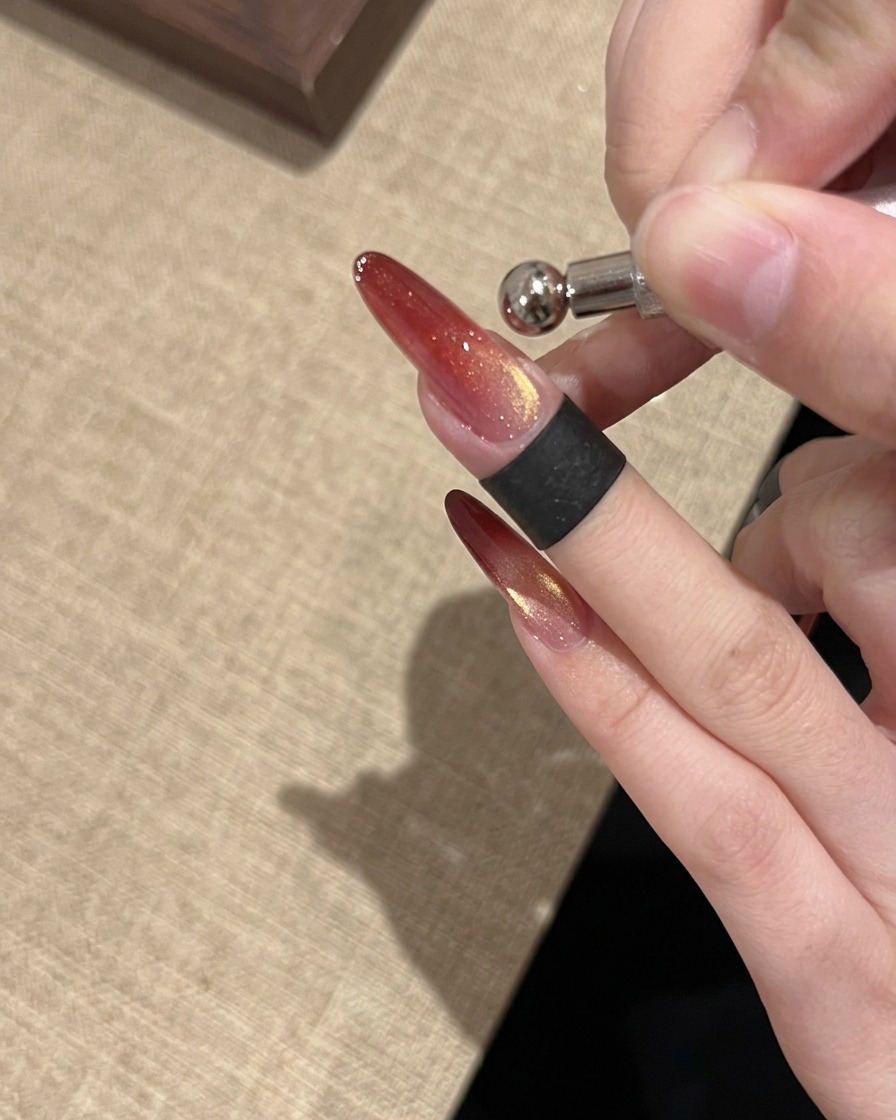 Un outil aimant anneau utilisé pour façonner une réflexion lumineuse cat eye perle de verre brillante et concentrée sur longle.