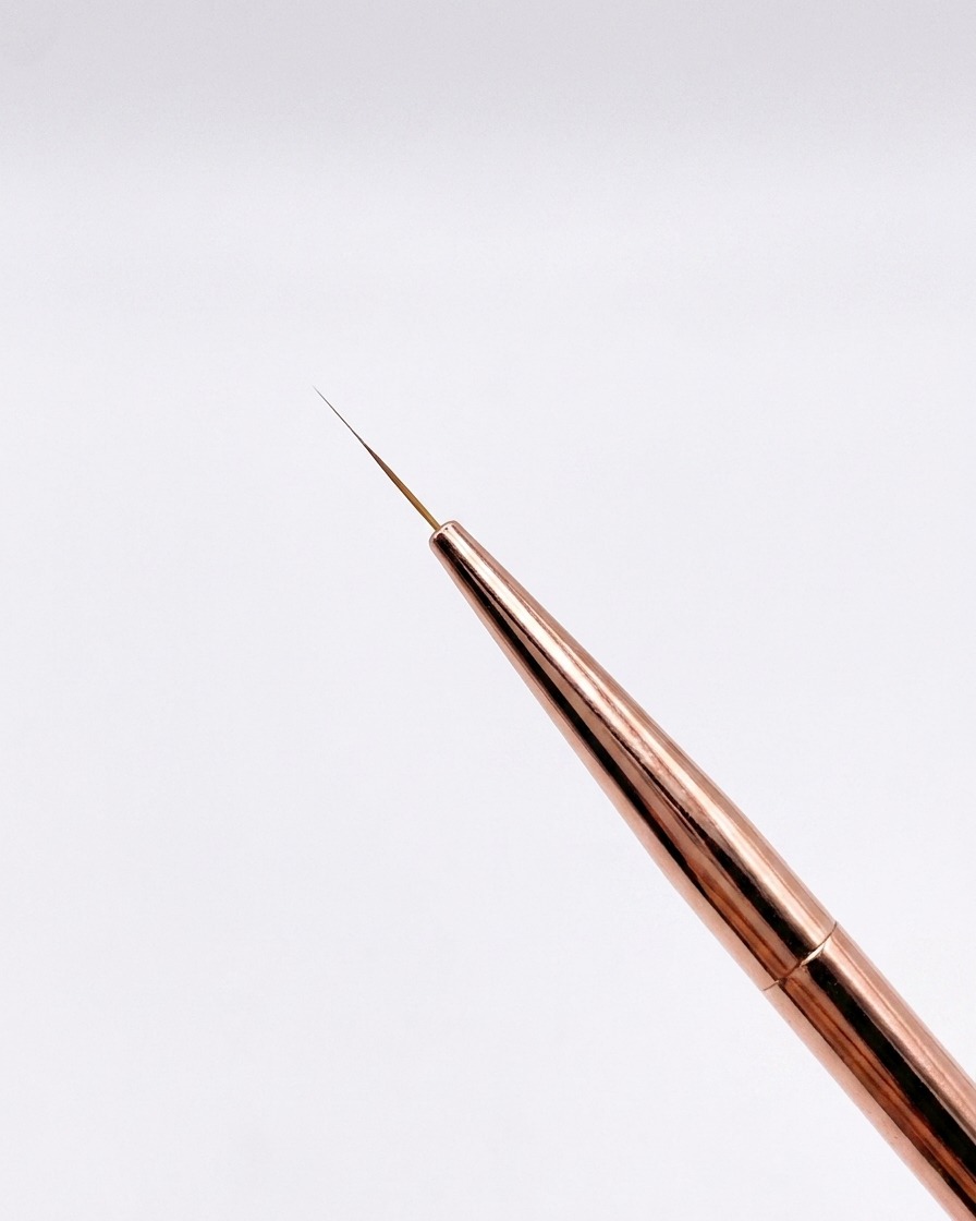 Gros plan dun pinceau fin or rose de 12 mm avec une pointe très effilée sur fond neutre.