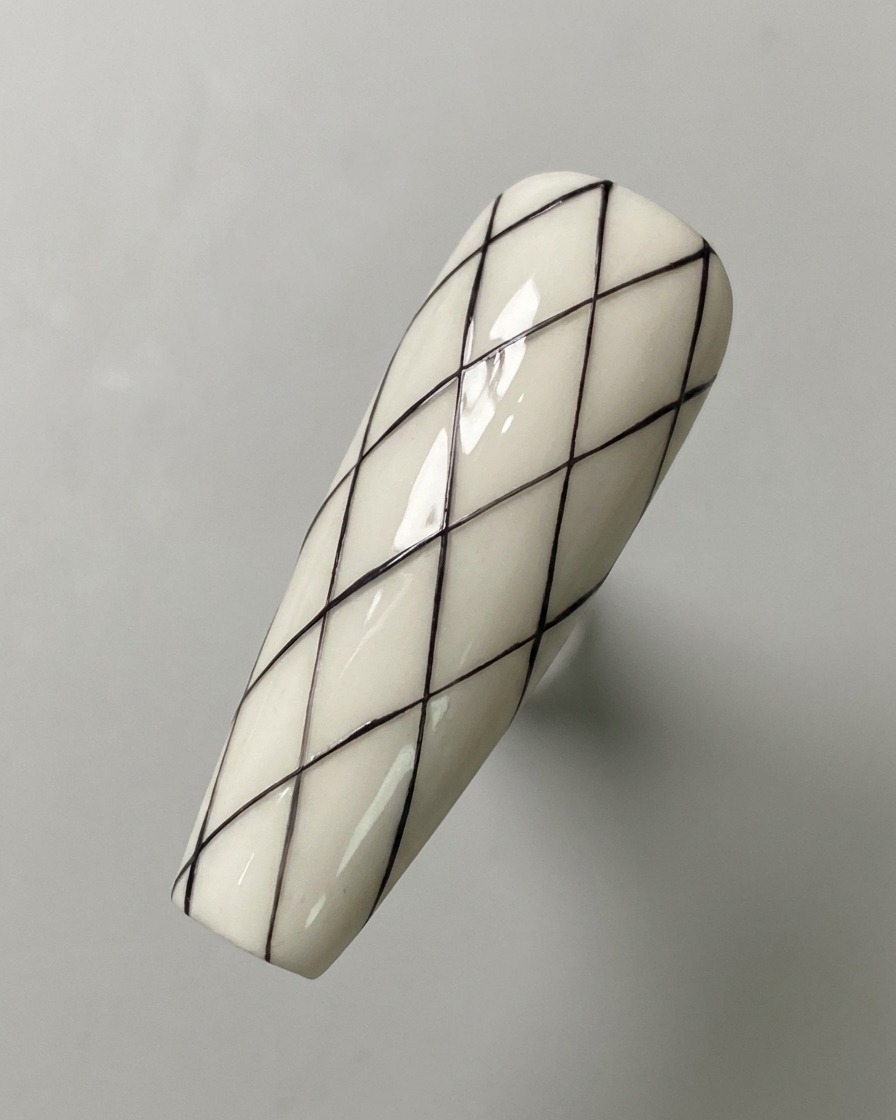 Un motif de grille de losanges noirs entièrement dessiné sur une surface dongle à base blanche.