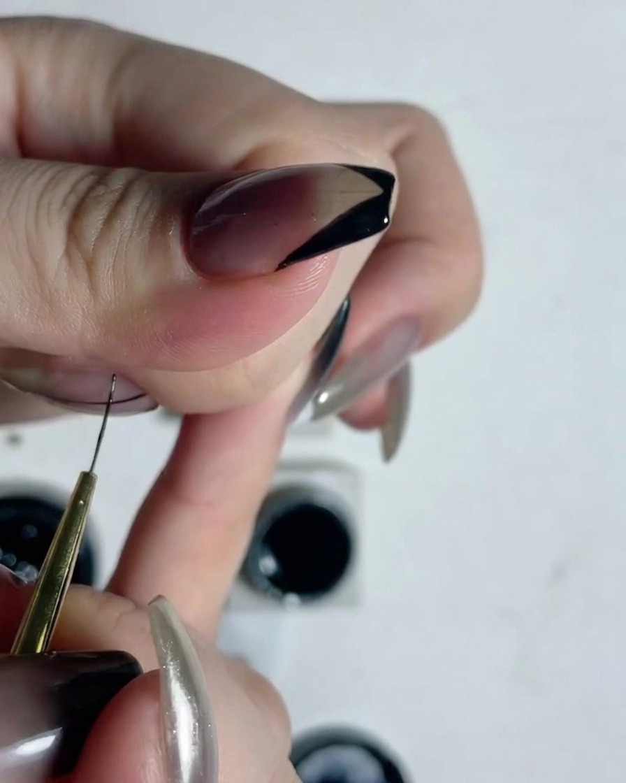 Vue rapprochée dun pinceau liner fin traçant des lignes verticales précises sur un ongle translucide.
