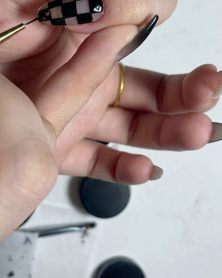 Un pinceau liner fin contournant le périmètre dun motif de damier noir et blanc achevé.