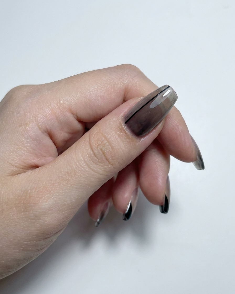 Une main montrant des ongles à dégradé translucide et french manucure finis avec un top coat ultra-brillant.