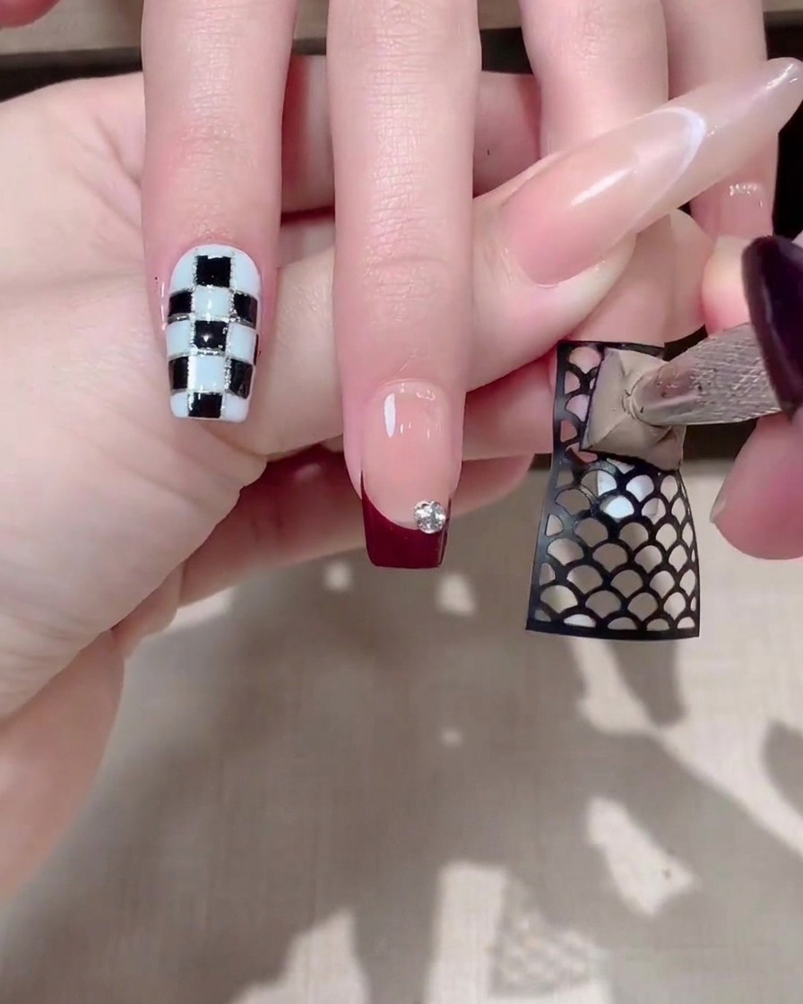Un outil en mousse tapotant un gel gris épais sur un sticker résille noir sur un ongle.