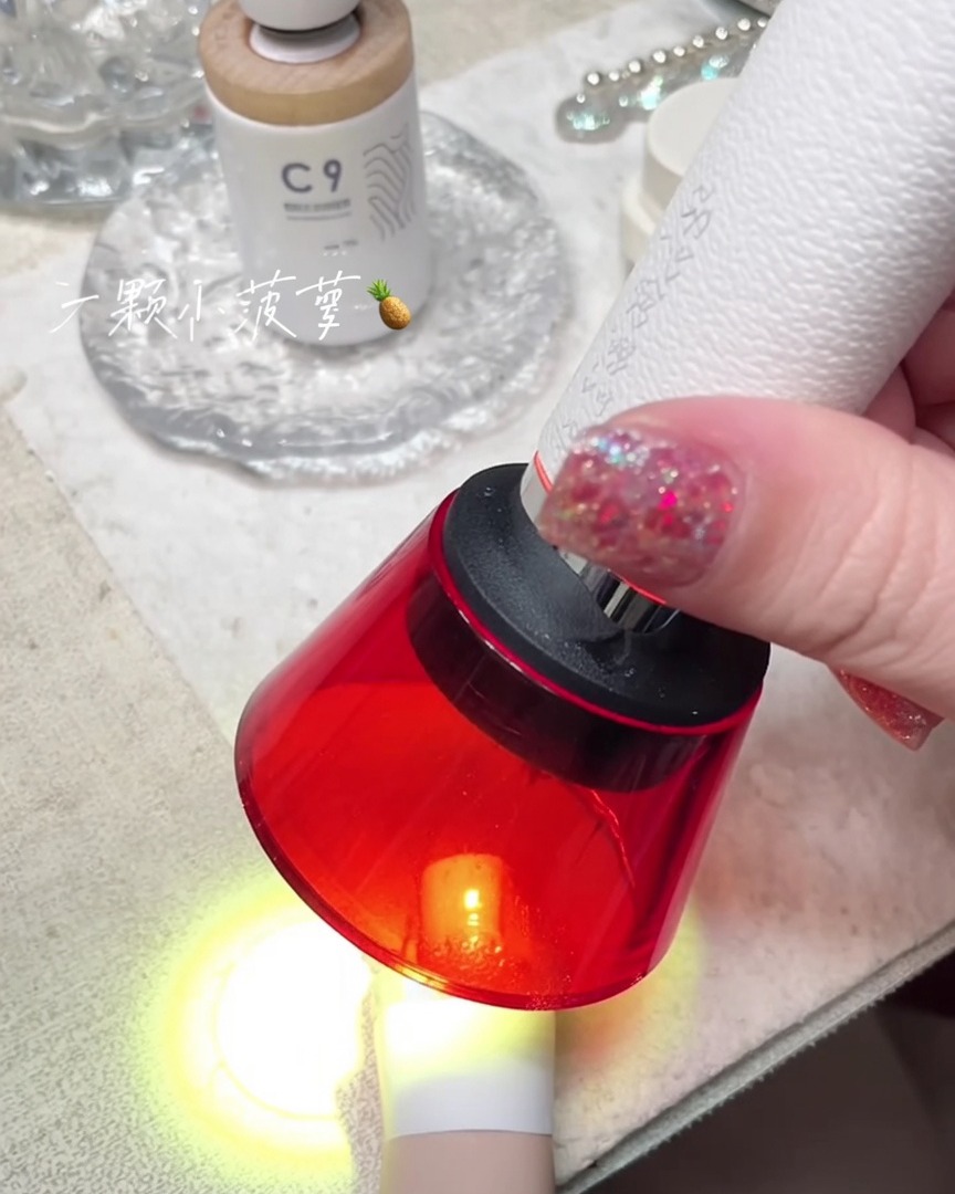 Une mini lampe UV rouge portable catalysant un ongle sur un doigt.