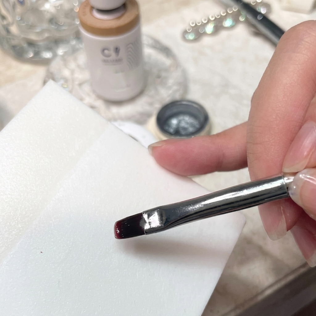Un gros plan détaillé dun pinceau mélangeant du vernis gel sur la surface dune palette blanche lisse.