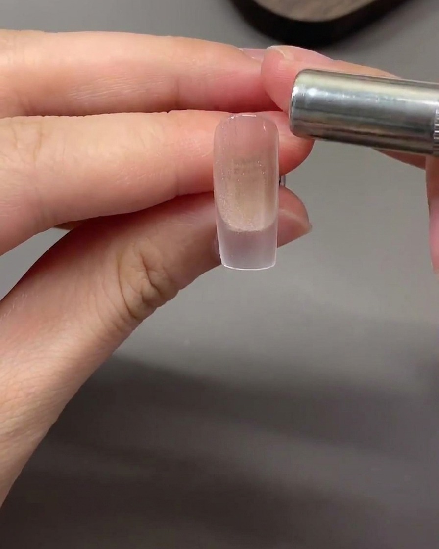 Un aimant cylindrique tenu horizontalement près de la pointe de longle pour attirer les particules magnétiques cat eye en une bande lumineuse.