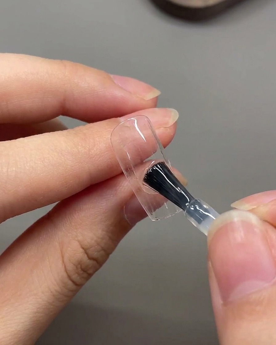 Un pinceau appliquant une couche de top coat mat sur toute la surface de longle.