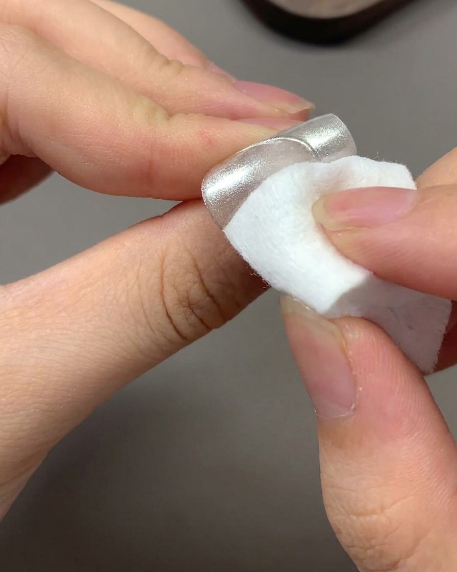 Une lingette sèche et propre éliminant lexcédent de poudre chrome volante dun ongle.