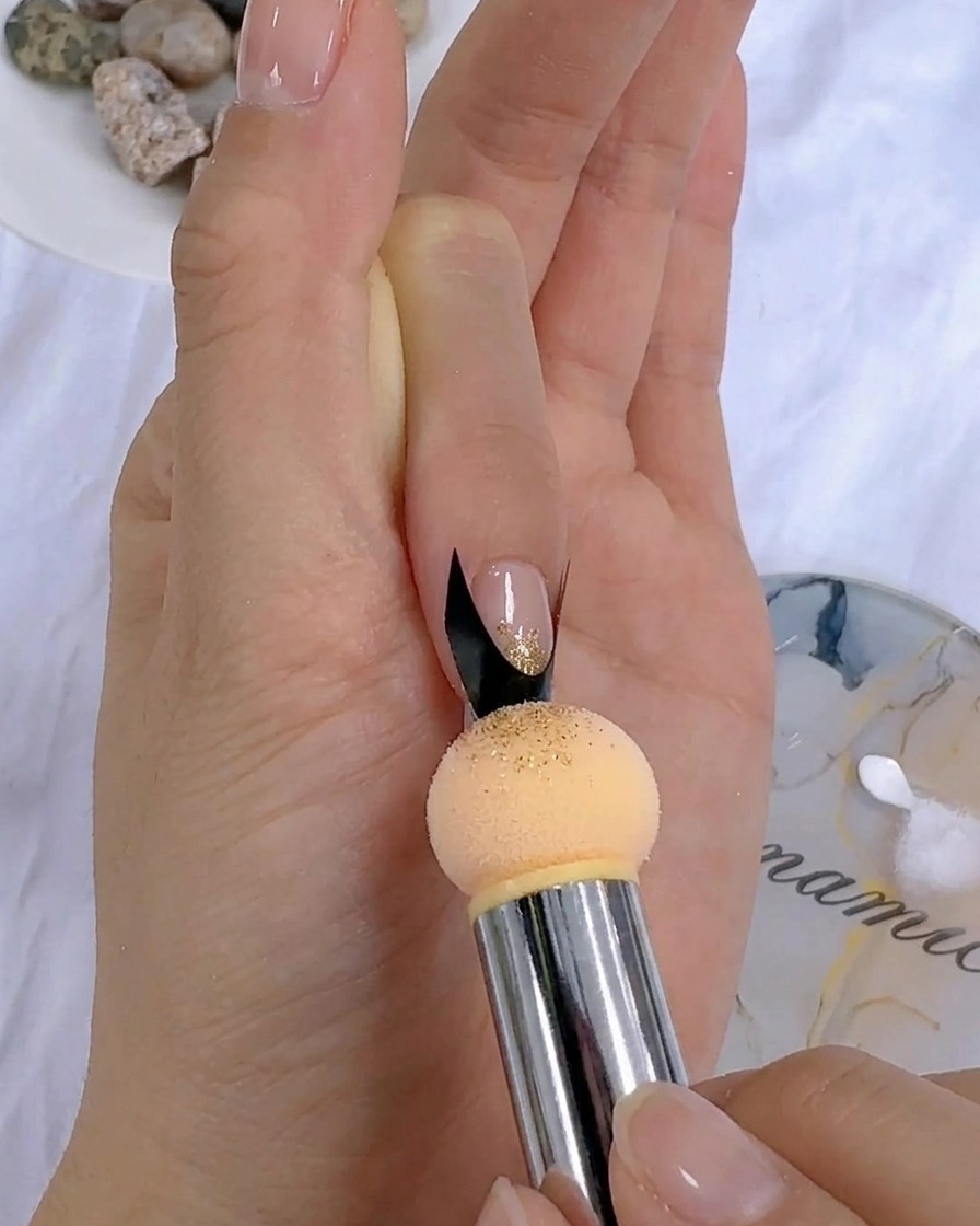 Une éponge appliquant par touches du gel de couleur sur un ongle près dun sticker français.