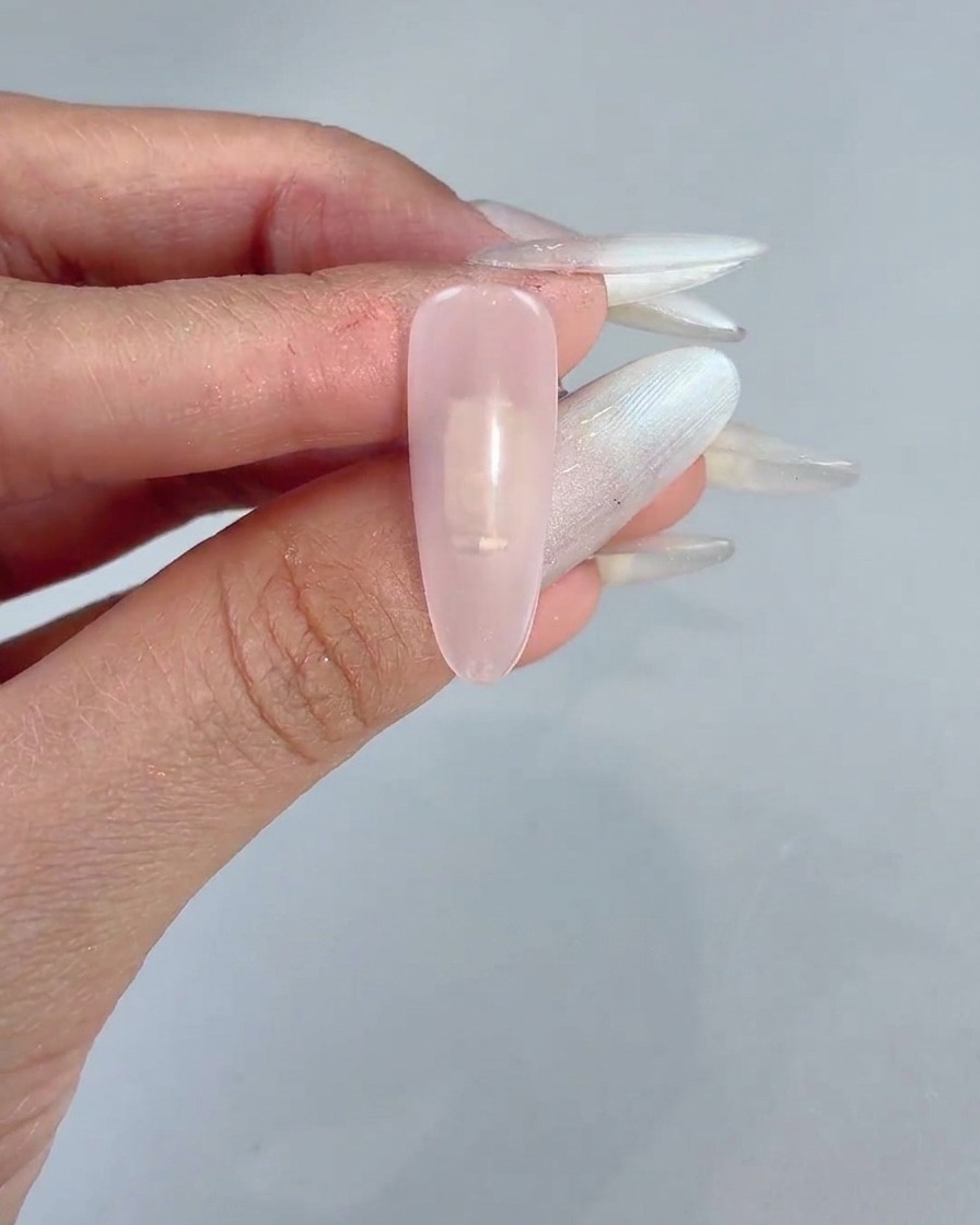 Un bloc-éponge tamponnant délicatement du gel rose sur le centre dun ongle manucuré et transparent.