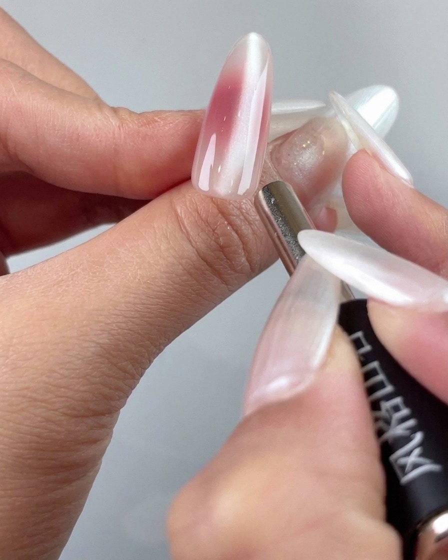 La pointe dun outil magnétique de précision ajustant les particules cat-eye près de la zone des cuticules dun ongle.