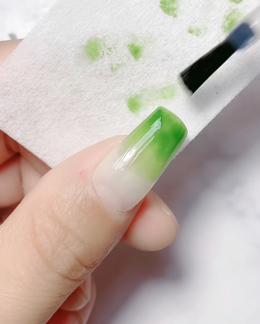 Un coton imbibé de dégraissant essuyant la couche dinhibition dun ongle dégradé catalysé.