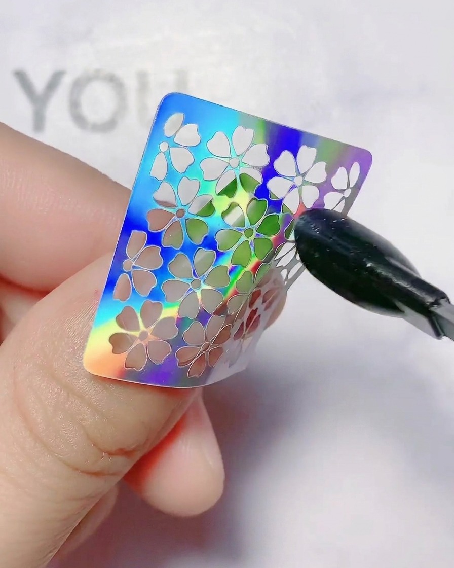 Un sticker de fleur creuse pressé sur un ongle en dégradé.
