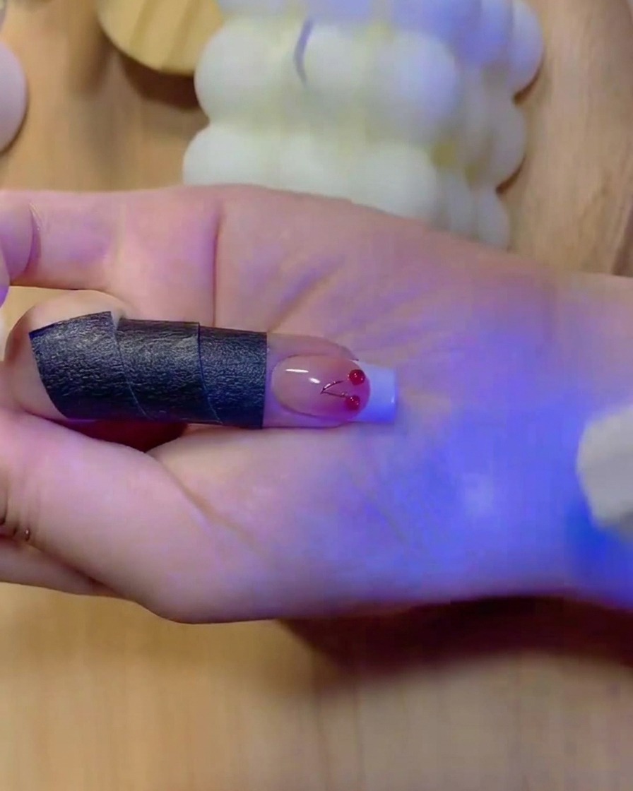 Un pinceau remplissant de couleur blanche unie le bout dune French manucure sur un ongle dégradé.