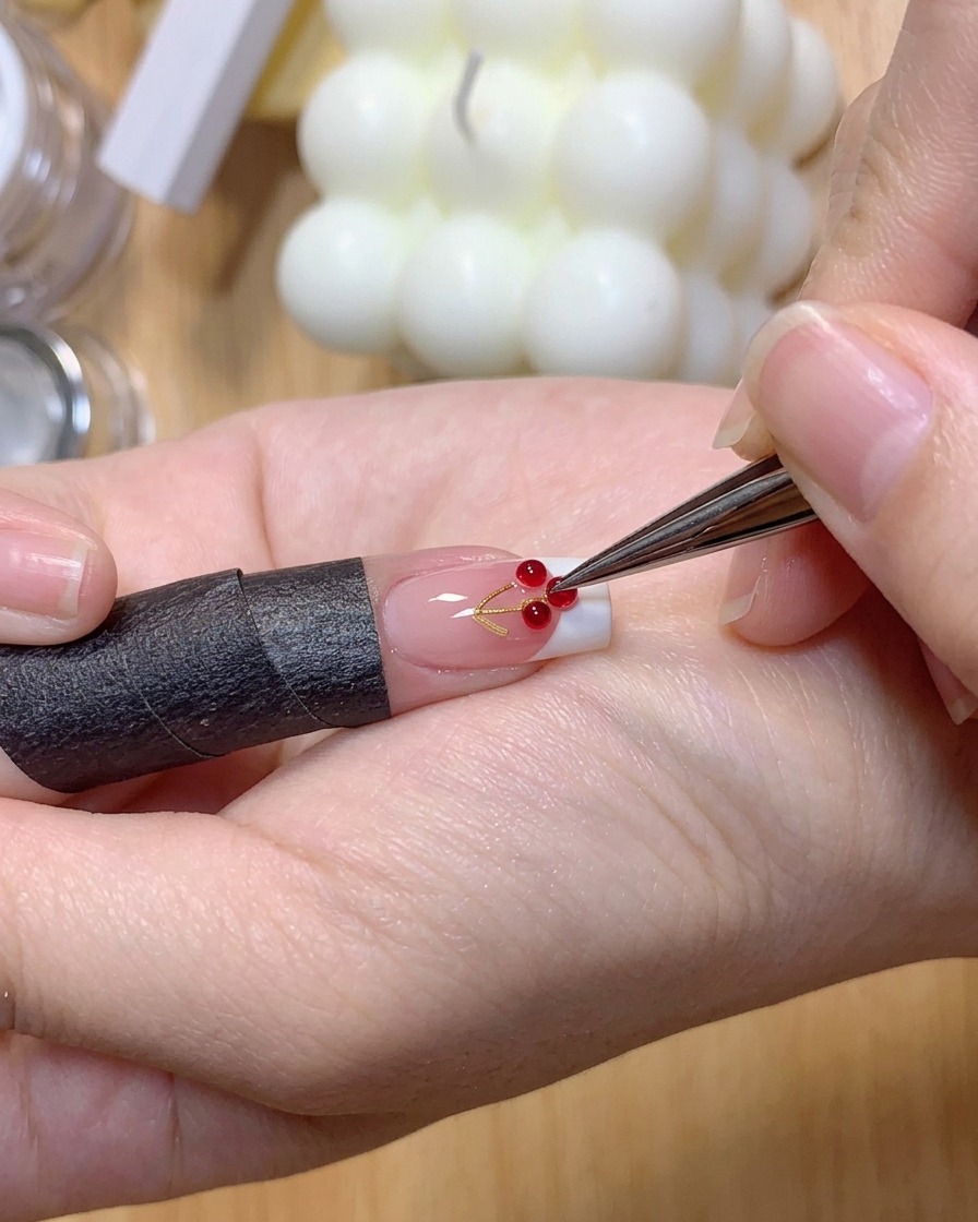 Une pince à épiler plaçant deux petites boules de gel transparent 3D sur la surface dun ongle avec une French.