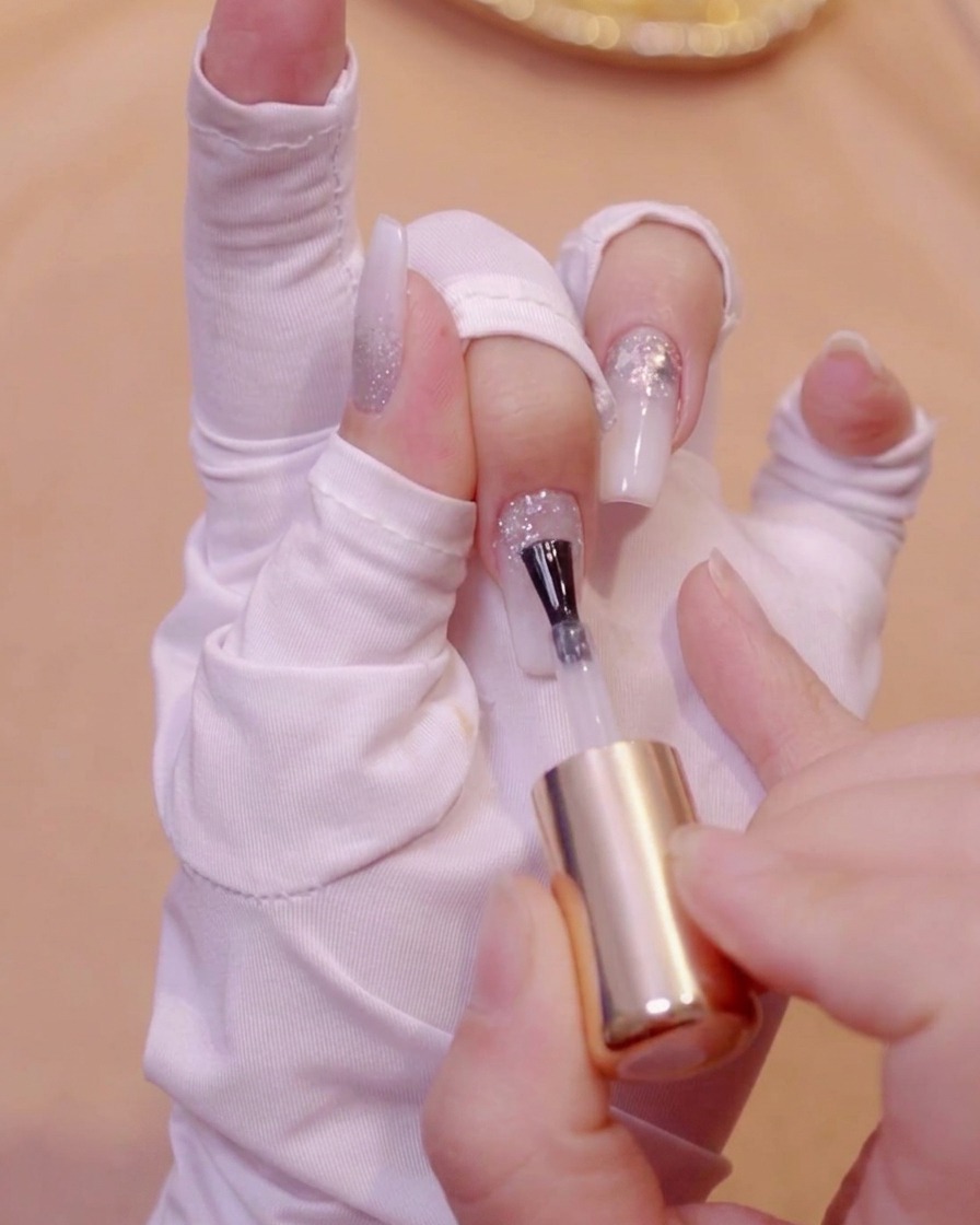 Un pinceau appliquant du gel transparent auto-égalisant sur une surface dongle pailletée texturée.