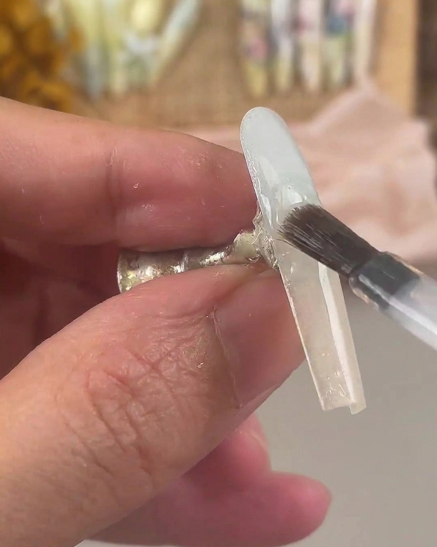 Un pinceau à ongles recouvrant longle dégradé dune couche de gel de base transparent.