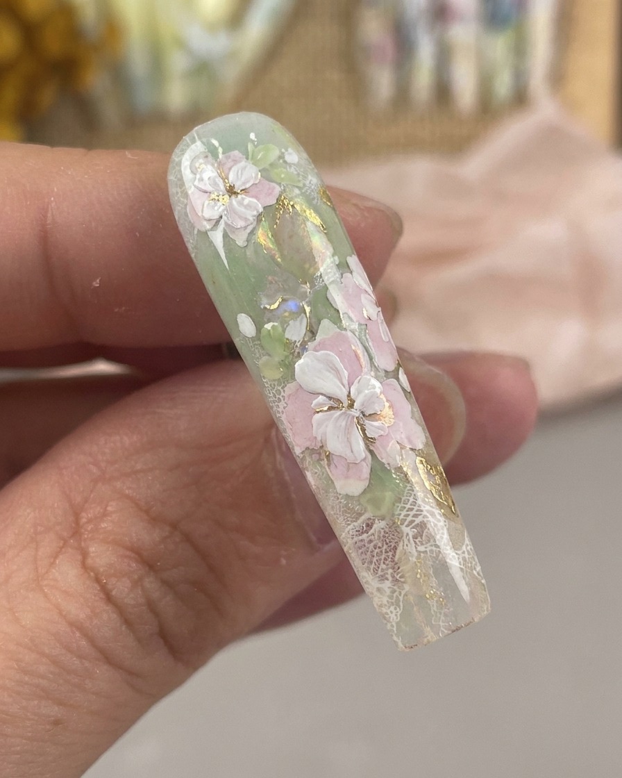 Gros plan dun pinceau de nail art ultra-fin dessinant de délicats pistils blancs et des points centraux sur un motif floral.