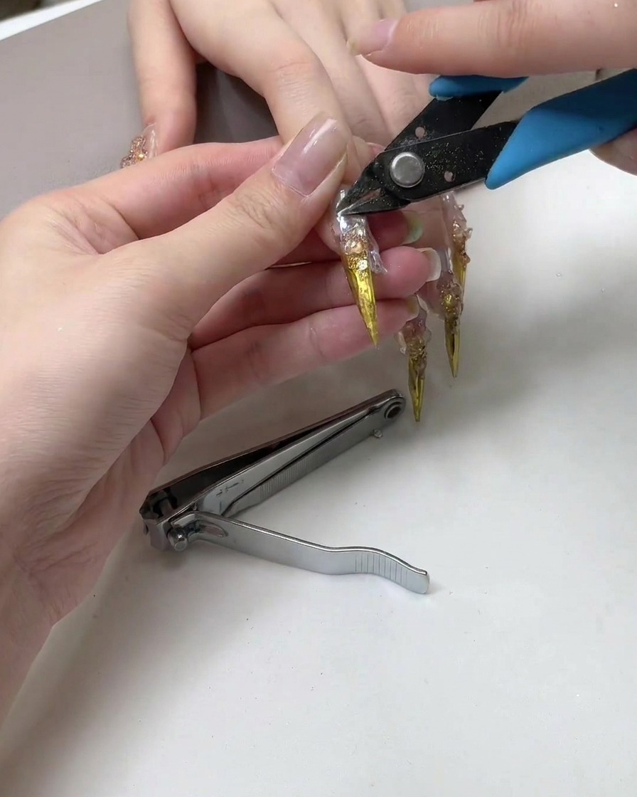 Un coupe-ongles coupant lextrémité pointue dune longue extension dongle métallique.